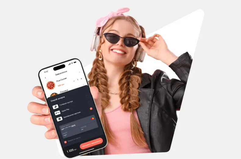 Дівчина показує сторінку оплати від сервісу hutko на своєму смартфоні